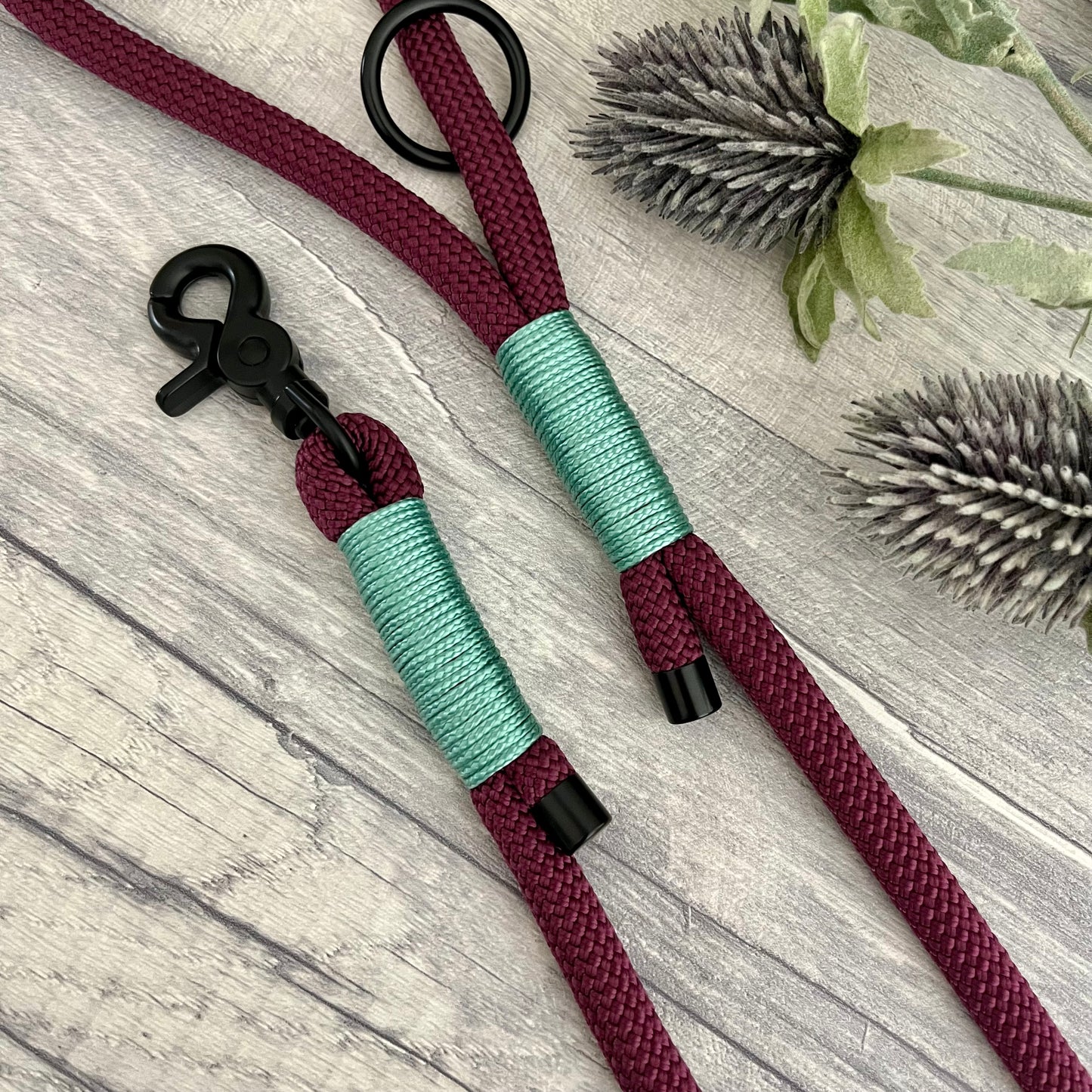 Aubergine rope lead with Sea Green whipping securing a swivel clip at one end with whipping securing a handle at the other. The ends of the rope ends are finished with metal end caps. All hardware is in Black