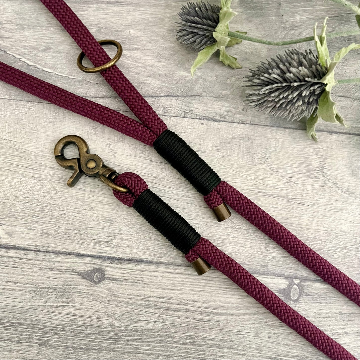 Aubergine rope lead with Black whipping securing a swivel clip at one end with whipping securing a handle at the other. The ends of the rope ends are finished with metal end caps. All hardware is in Antique Brass