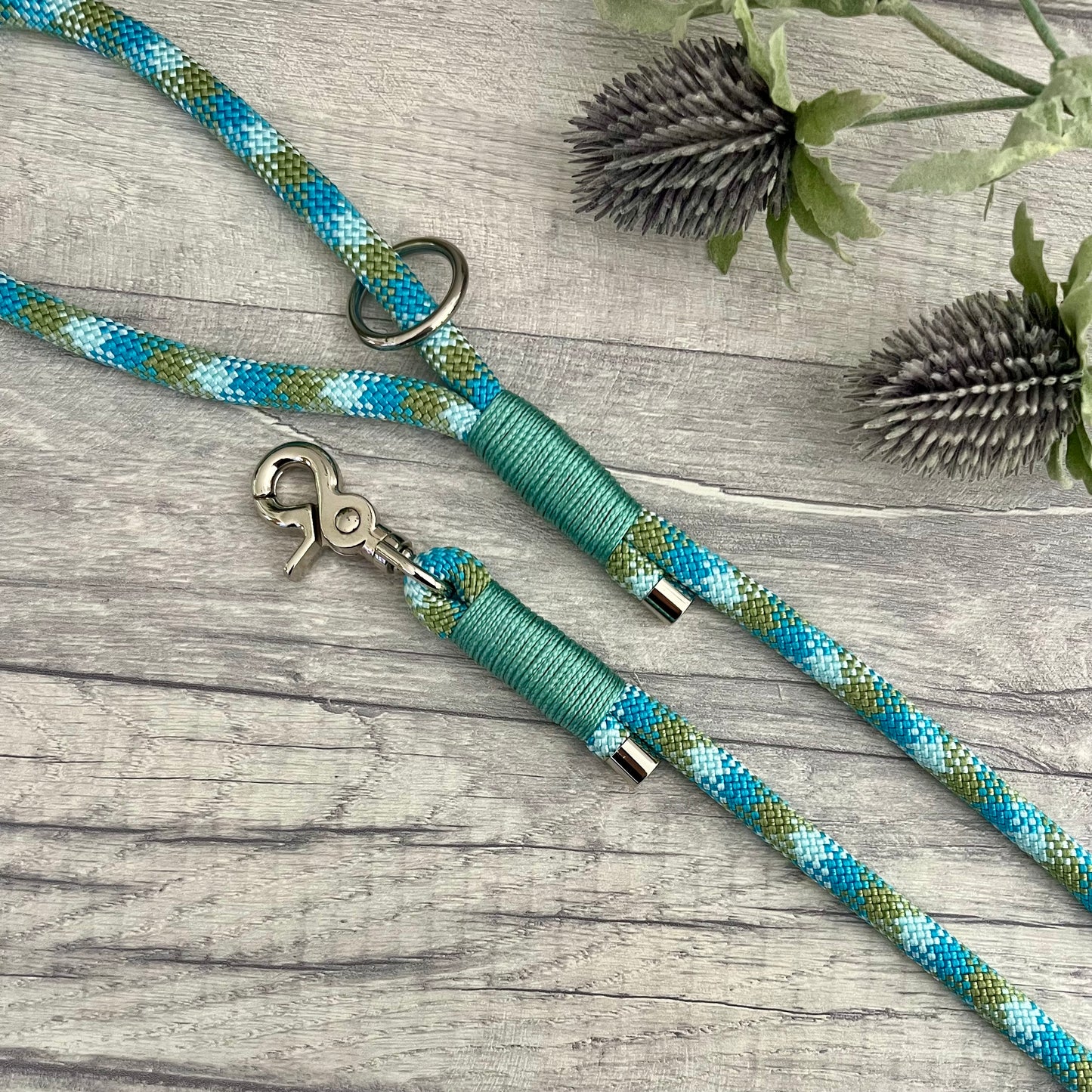 Bombay Blue rope lead with Sea Green whipping securing a swivel clip at one end and fastening a handle at the other. The handle has an O-ring attached. Each end of the rope is finished with a metal end cap. All hardware for this lead is in Silver
