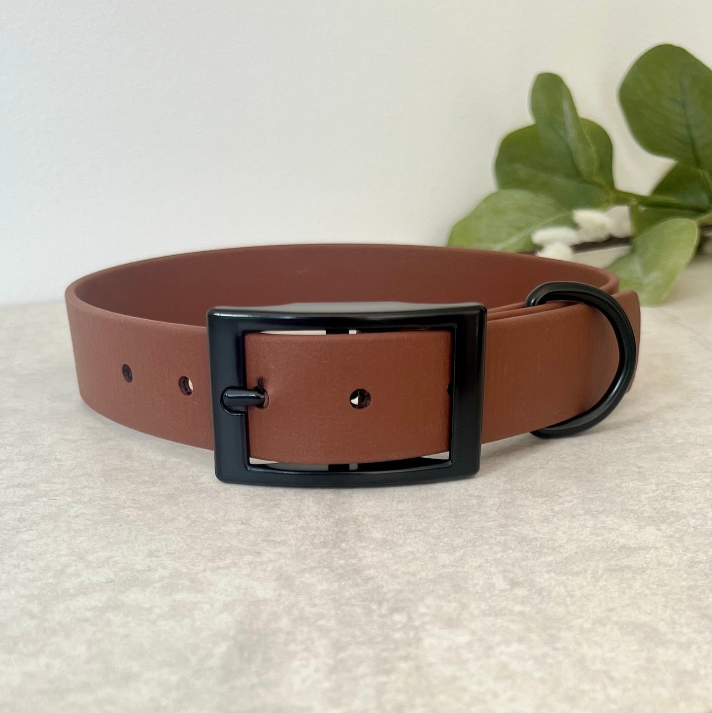 Biothane custom collar in Brown with Black buckle and a D-ring. The collar has 5 holes which are spaced 2cm apart. The collar is fastened on the first hole and has a soft leather appearance