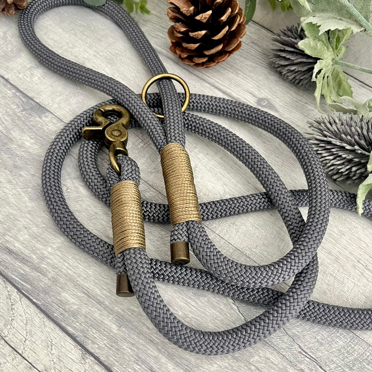 Charcoal Grey rope lead with Gold Brown whipping securing a swivel clip at one end and fastening a handle at the other. The handle has an O-ring attached. Each end of the rope is finished with a metal end cap. All hardware for this lead is in Antique Brass