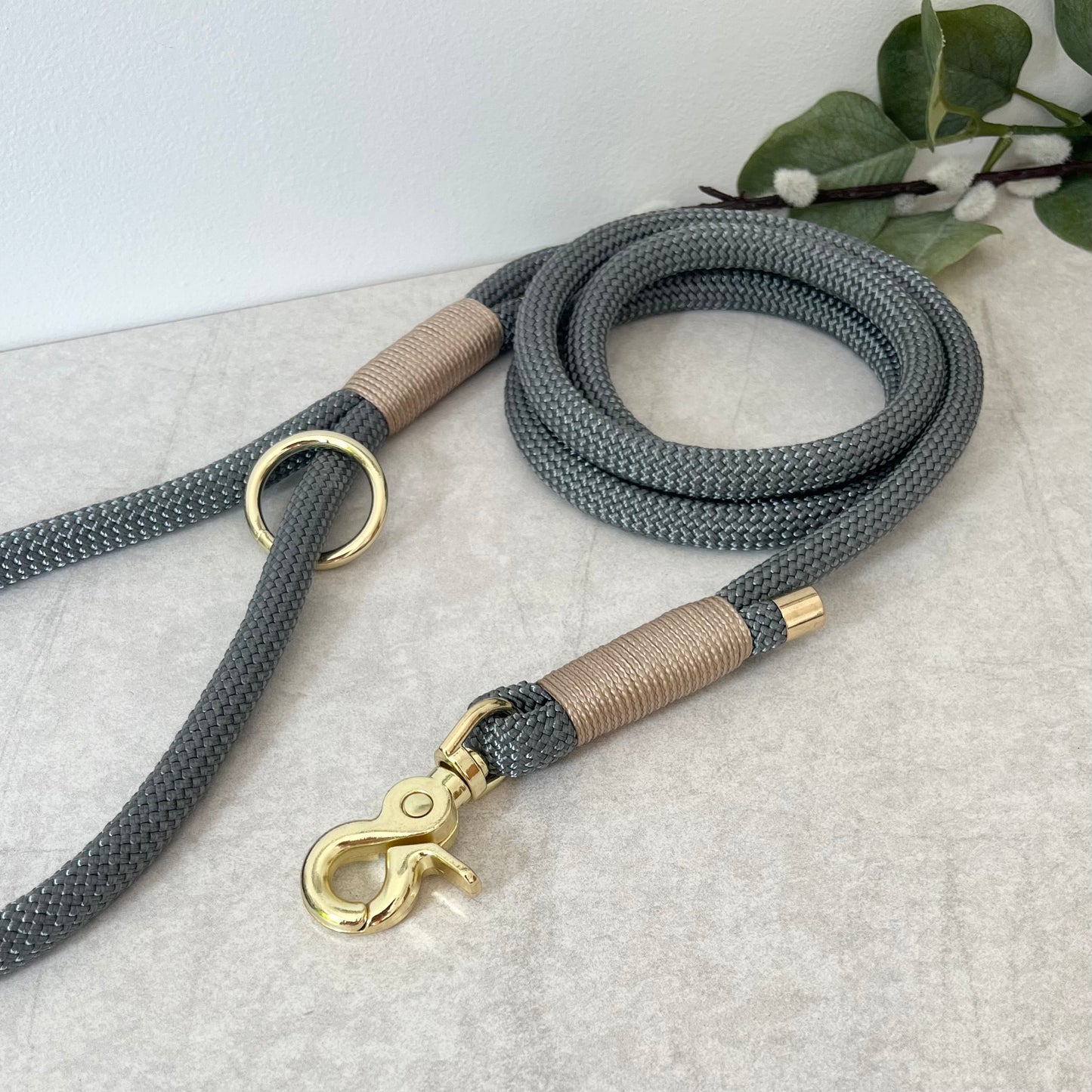 Charcoal Grey rope lead with Light Gold whipping securing a swivel clip at one end and fastening a handle at the other. The handle has an O-ring attached. Each end of the rope is finished with a metal end cap. All hardware for this lead is in Gold