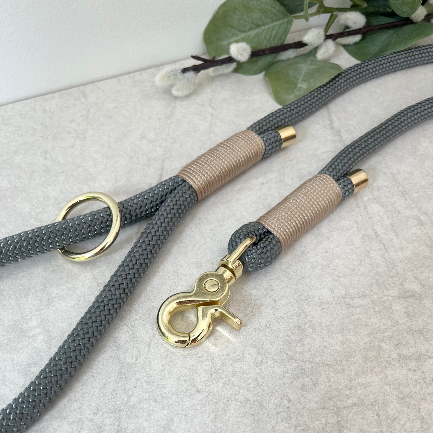 Charcoal Grey rope lead with Light Gold whipping securing a swivel clip at one end and fastening a handle at the other. The handle has an O-ring attached. Each end of the rope is finished with a metal end cap. All hardware for this lead is in Gold