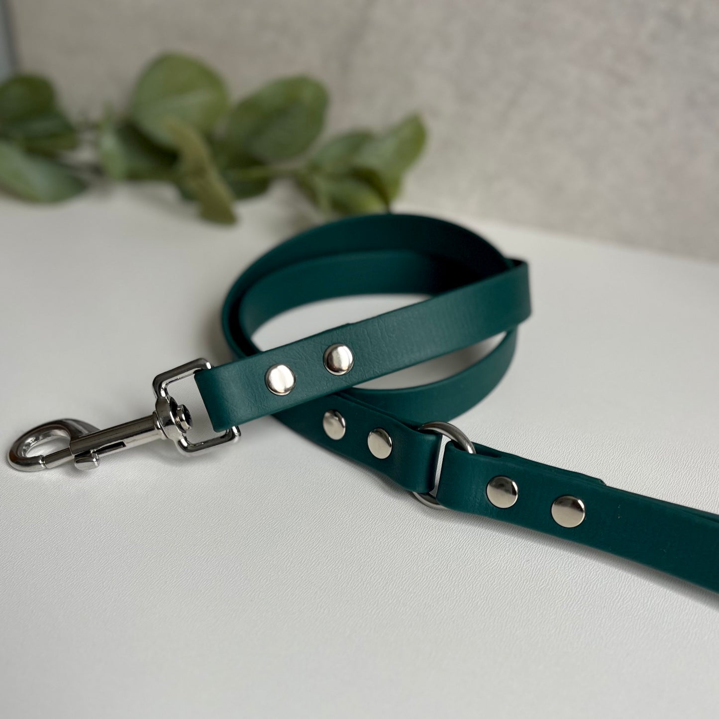 Dark Green Biothane lead with Silver Hardware. An O-ring connects the handle to the lead with double ended rivets fixing it together. A Snap Clip is fixed with double ended rivets. The lead has a soft leather appearance.