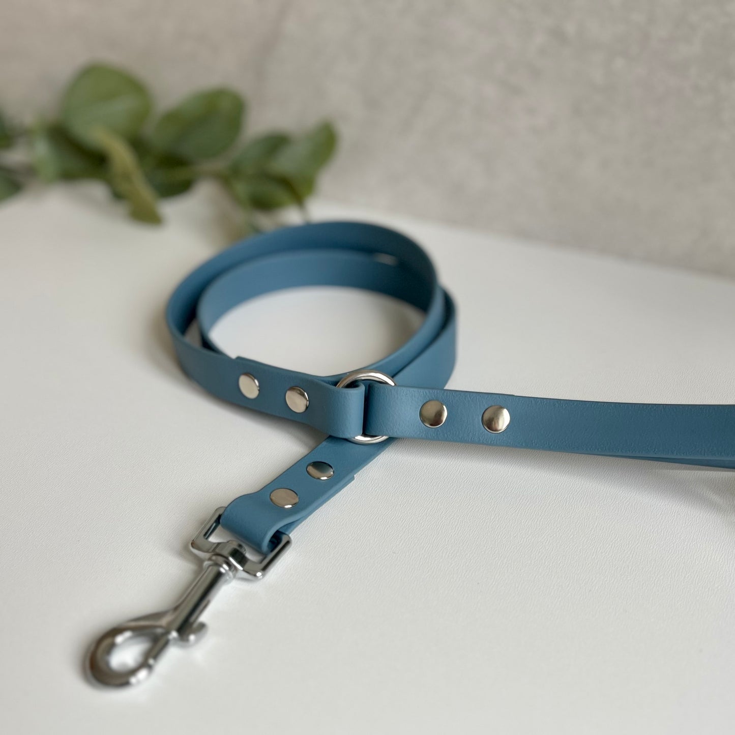 Petrol Blue Biothane lead with Silver Hardware. An O-ring connects the handle to the lead with double ended rivets fixing it together. A Snap Clip is fixed with double ended rivets. The lead has a soft leather appearance.