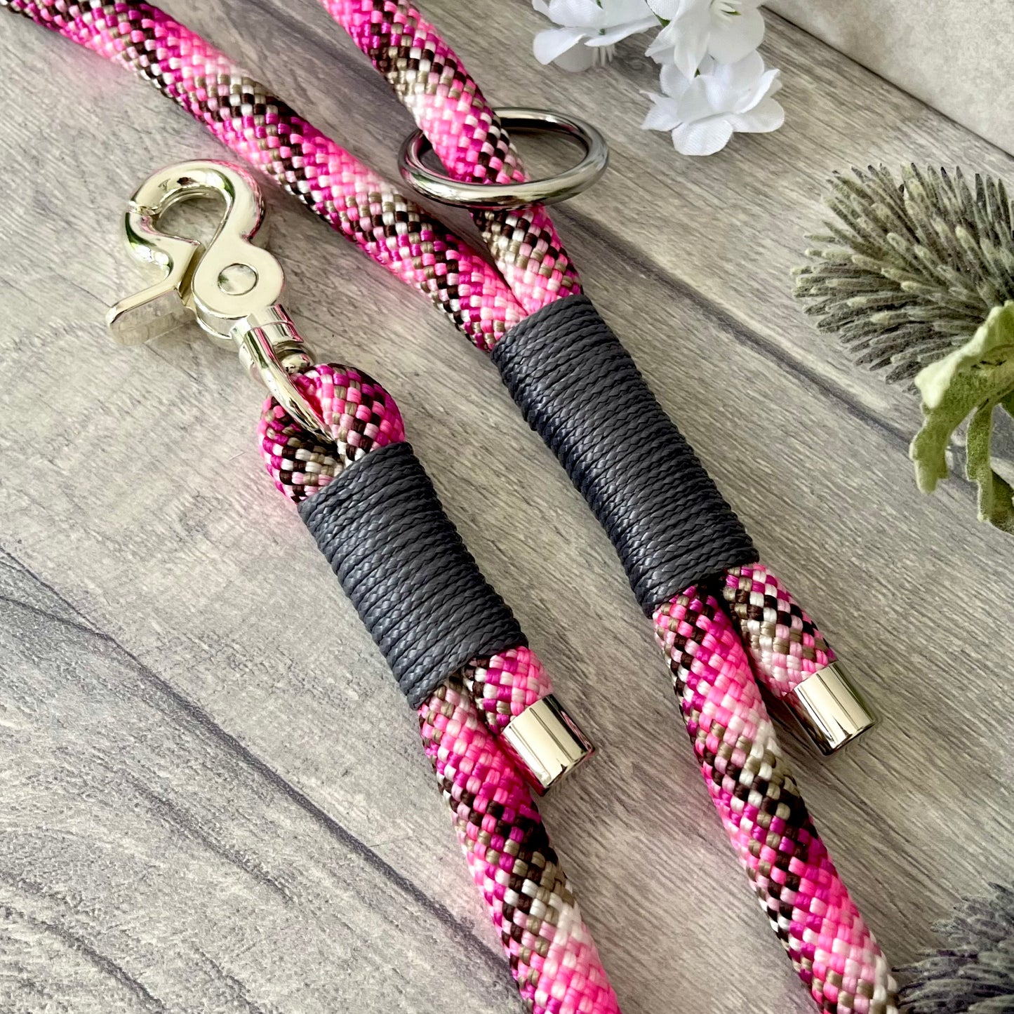 Cowgirl, pink rope lead with Charcoal whipping securing a swivel clip at one end and fastening a handle at the other. The handle has an O-ring attached. Each end of the rope is finished with a metal end cap. All hardware for this lead is in Silver