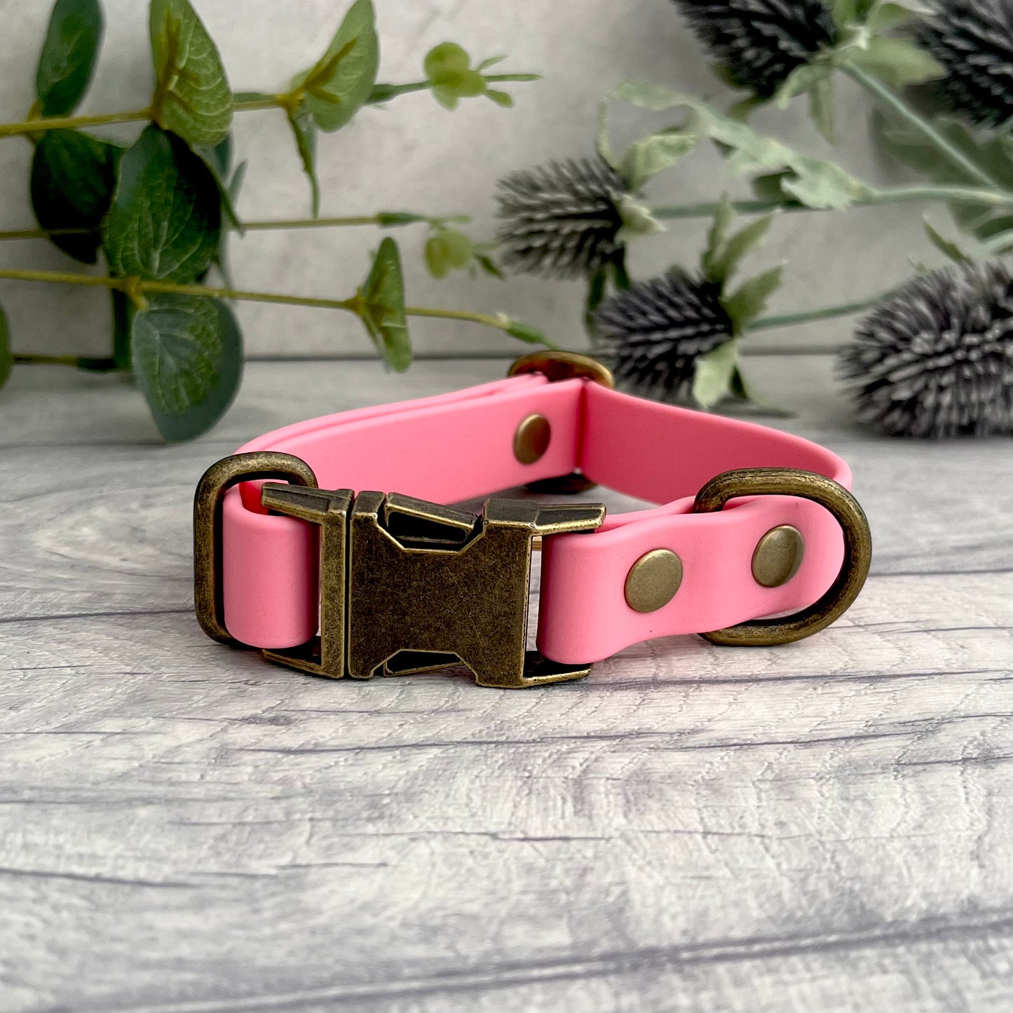 Made from Biothane in Pink, the collar is fastened with a metal quick release buckle, metal rivets with a metal strap keeper on one side with a D-ring on the other. All hardware is in Antique Brass