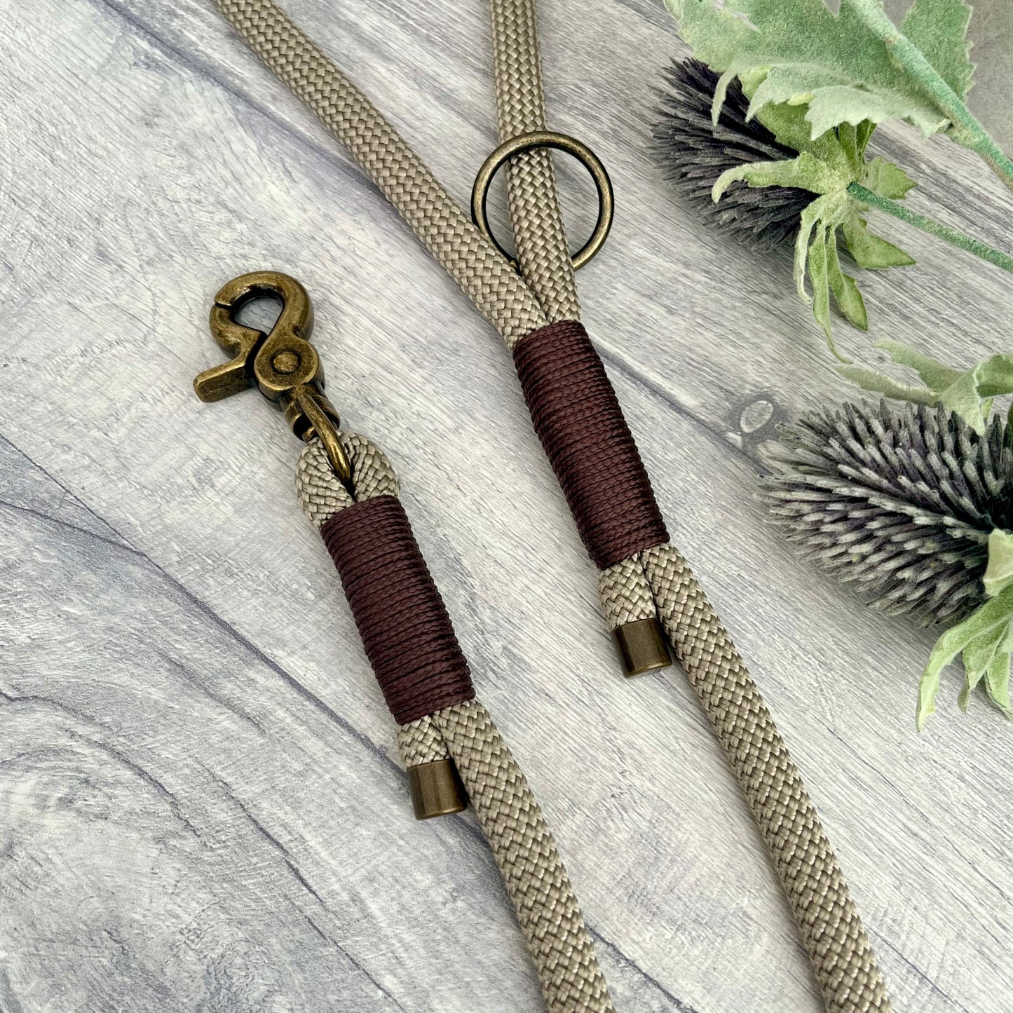 Tan rope dog lead with Brown whipping securing a swivel clip at one end with whipping securing a handle at the other. The ends of the rope ends are finished with metal end caps. All hardware is in Antique Brass