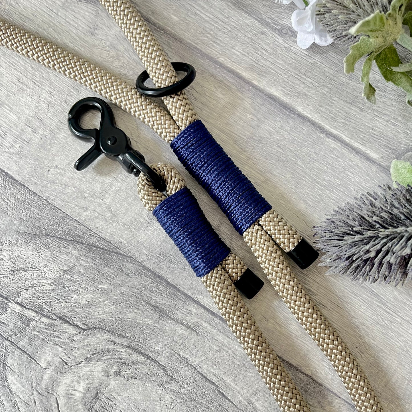 Tan rope dog lead with Dark Blue whipping securing a swivel clip at one end with whipping securing a handle at the other. The ends of the rope ends are finished with metal end caps. All hardware is in Black