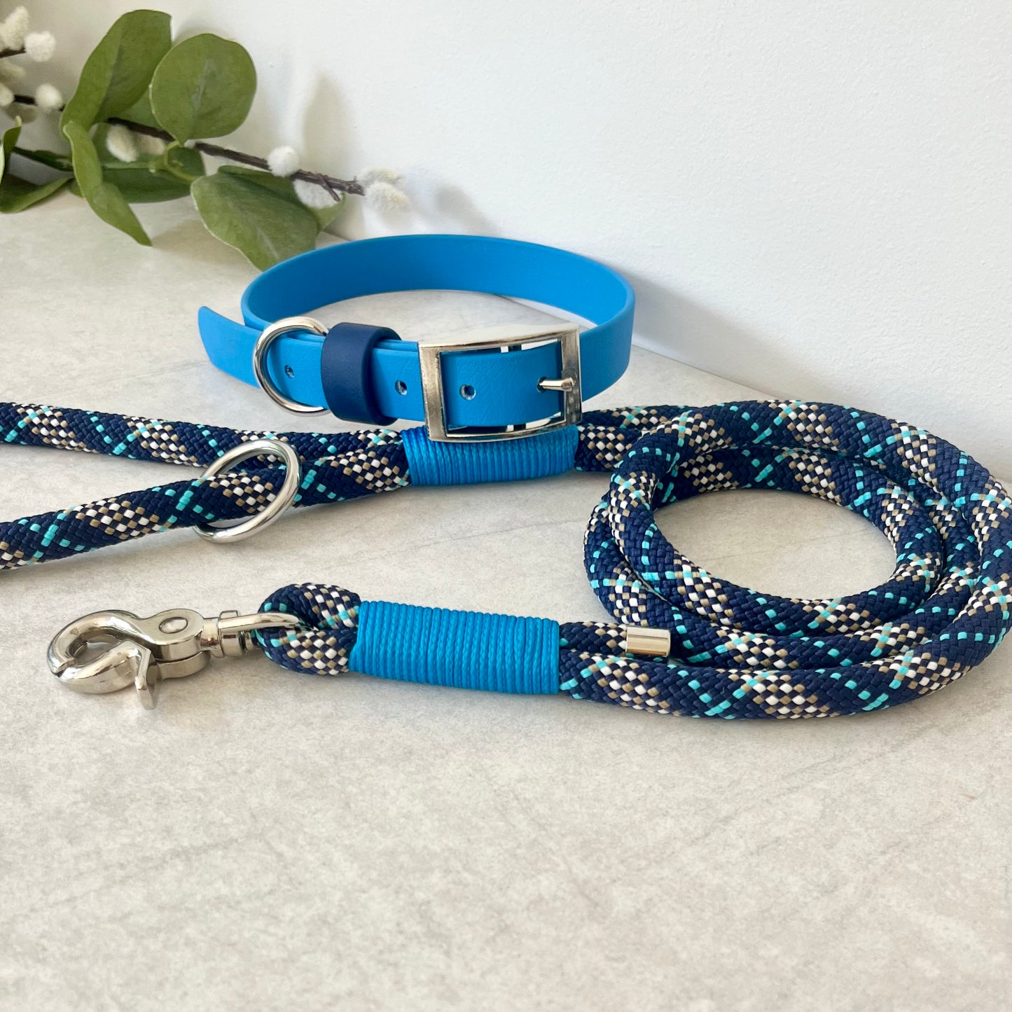 Tartan Blue rope lead with Royal Blue whipping securing a swivel clip at one end and fastening a handle at the other. The handle has an O-ring attached. Each end of the rope is finished with a metal end cap. All hardware for this lead is in Silver