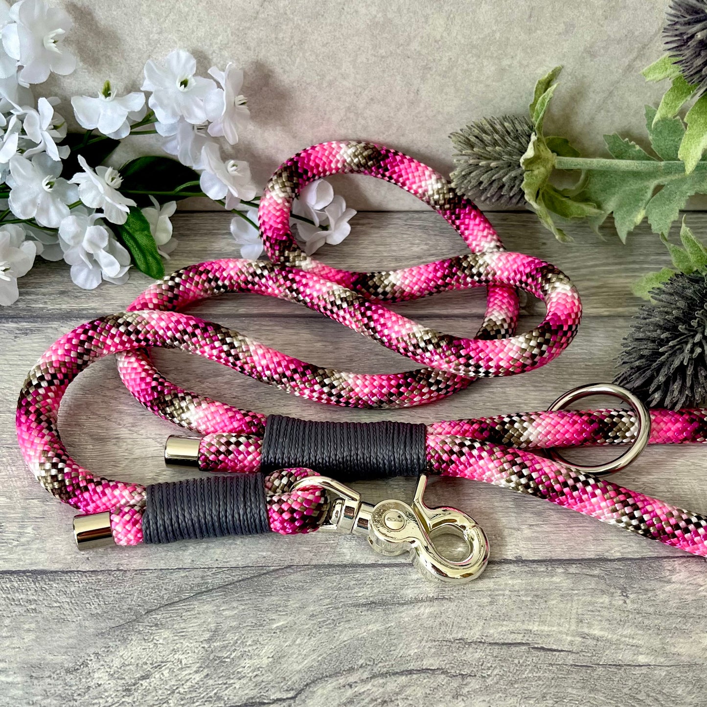 Cowgirl, pink rope lead with Charcoal whipping securing a swivel clip at one end and fastening a handle at the other. The handle has an O-ring attached. Each end of the rope is finished with a metal end cap. All hardware for this lead is in Silver