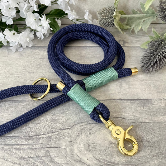 Marine Blue rope lead with Sea Green whipping securing a swivel clip at one end and fastening a handle at the other. The handle has an O-ring attached. Each end of the rope is finished with a metal end cap. All hardware for this lead is in Gold