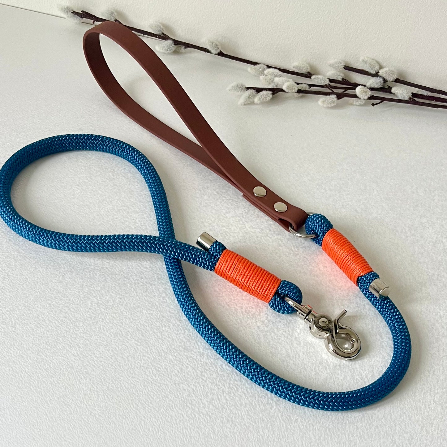 Blue rope dog lead with a brown BioThane handle, orange binding and silver hardware