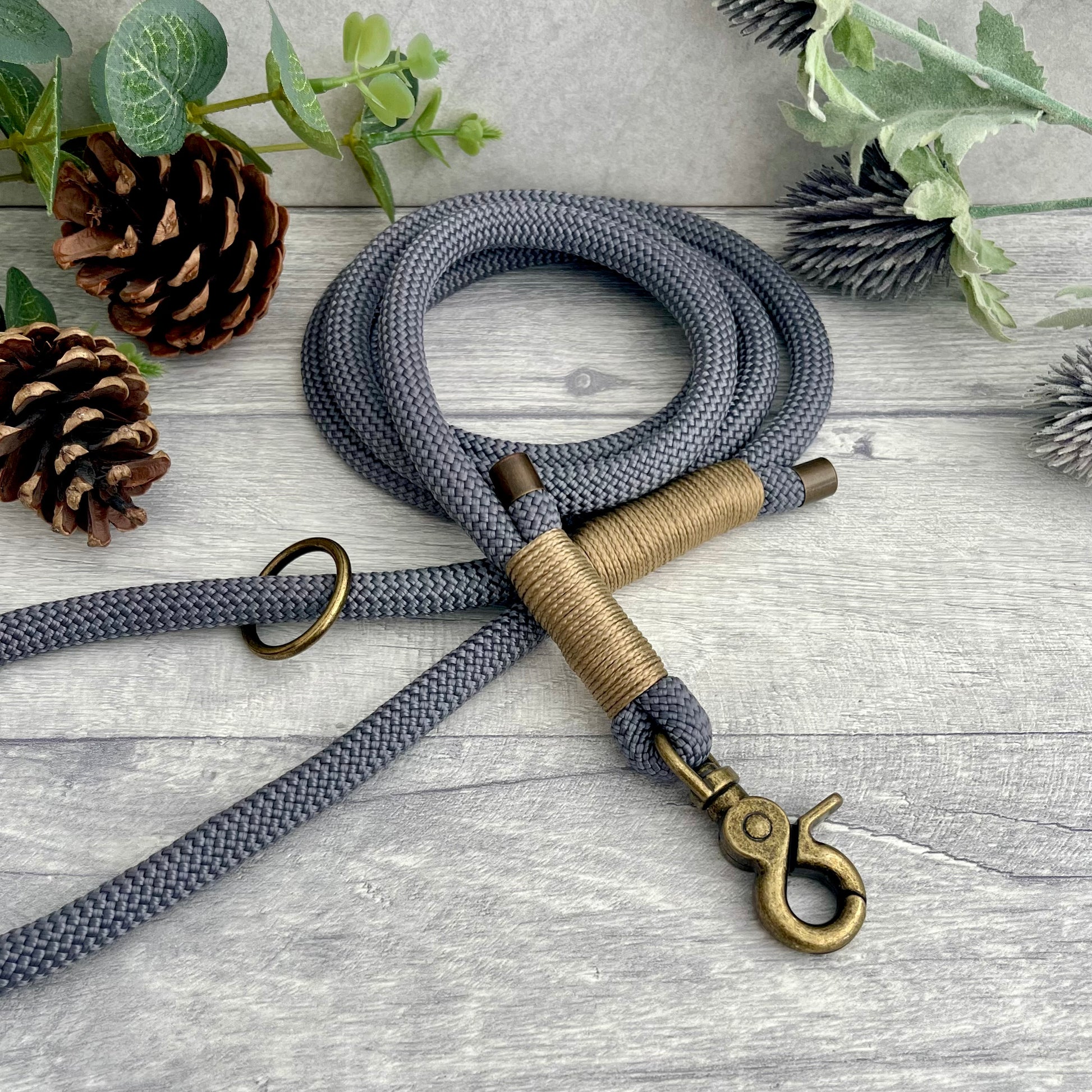 Charcoal Grey rope lead with Gold Brown whipping securing a swivel clip at one end and fastening a handle at the other. The handle has an O-ring attached. Each end of the rope is finished with a metal end cap. All hardware for this lead is in Antique Brass