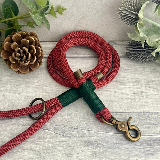 Copper Red Paracord rope lead with Dark Green whipping securing each end together. At each end of the rope there is a metal end cap, a clip to connect to a collar at one end and a O-ring fixed to the handle. All hardware is Antique Brass