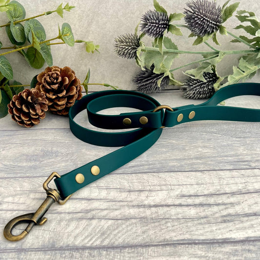 Dark Green Biothane lead with Antique Brass Hardware. An O-ring connects the handle to the lead with double ended rivets fixing it together. A Snap Clip is fixed with double ended rivets. The lead has a soft leather appearance.