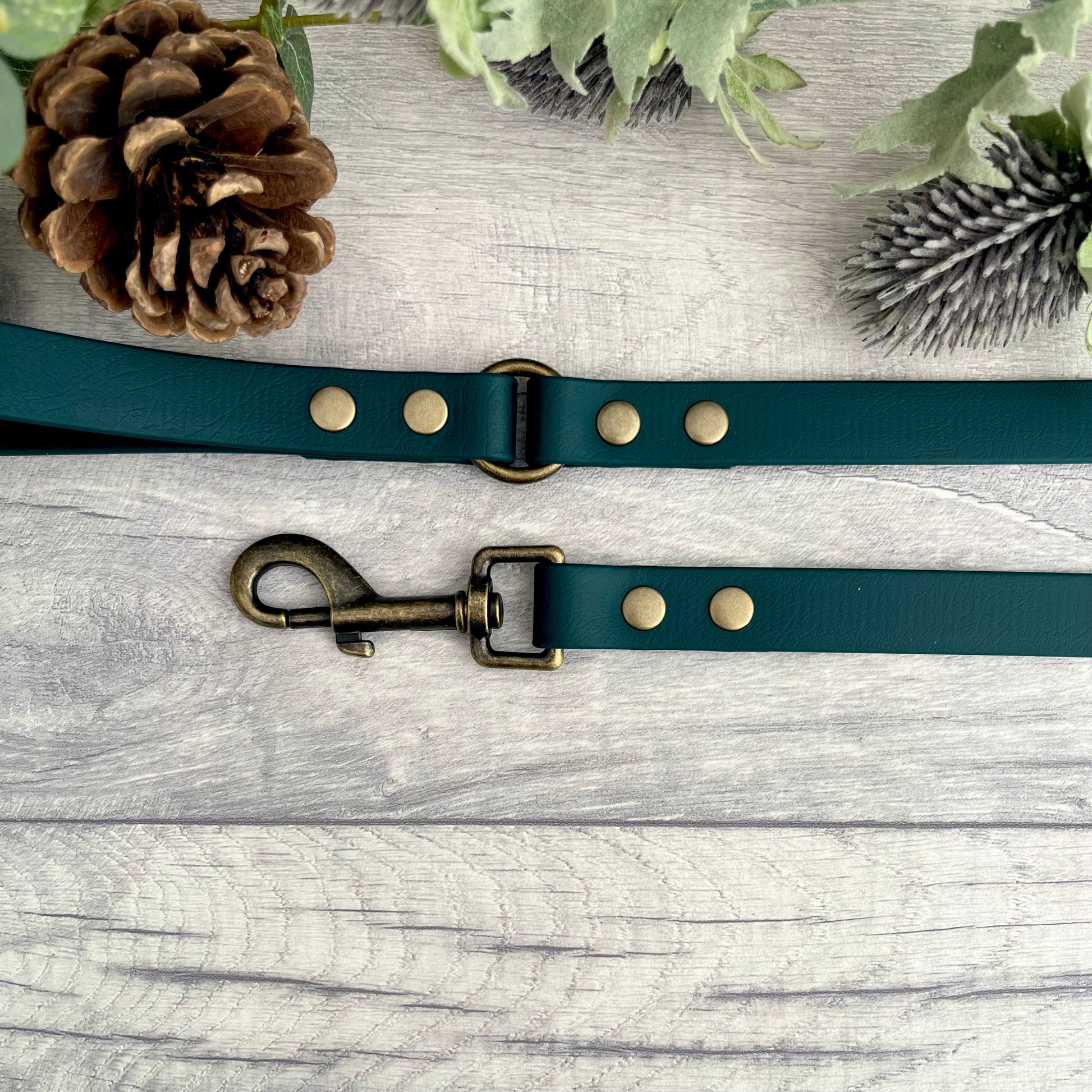 Dark Green Biothane lead with Antique Brass Hardware. An O-ring connects the handle to the lead with double ended rivets fixing it together. A Snap Clip is fixed with double ended rivets. The lead has a soft leather appearance.