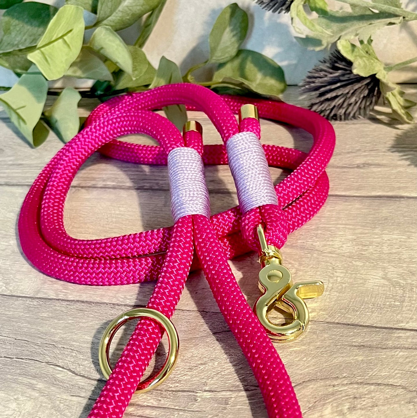 Fuchsia Pink rope lead with Lilac whipping securing a swivel clip at one end and fastening a handle at the other. The handle has an O-ring attached. Each end of the rope is finished with a metal end cap. All hardware for this lead is in Gold