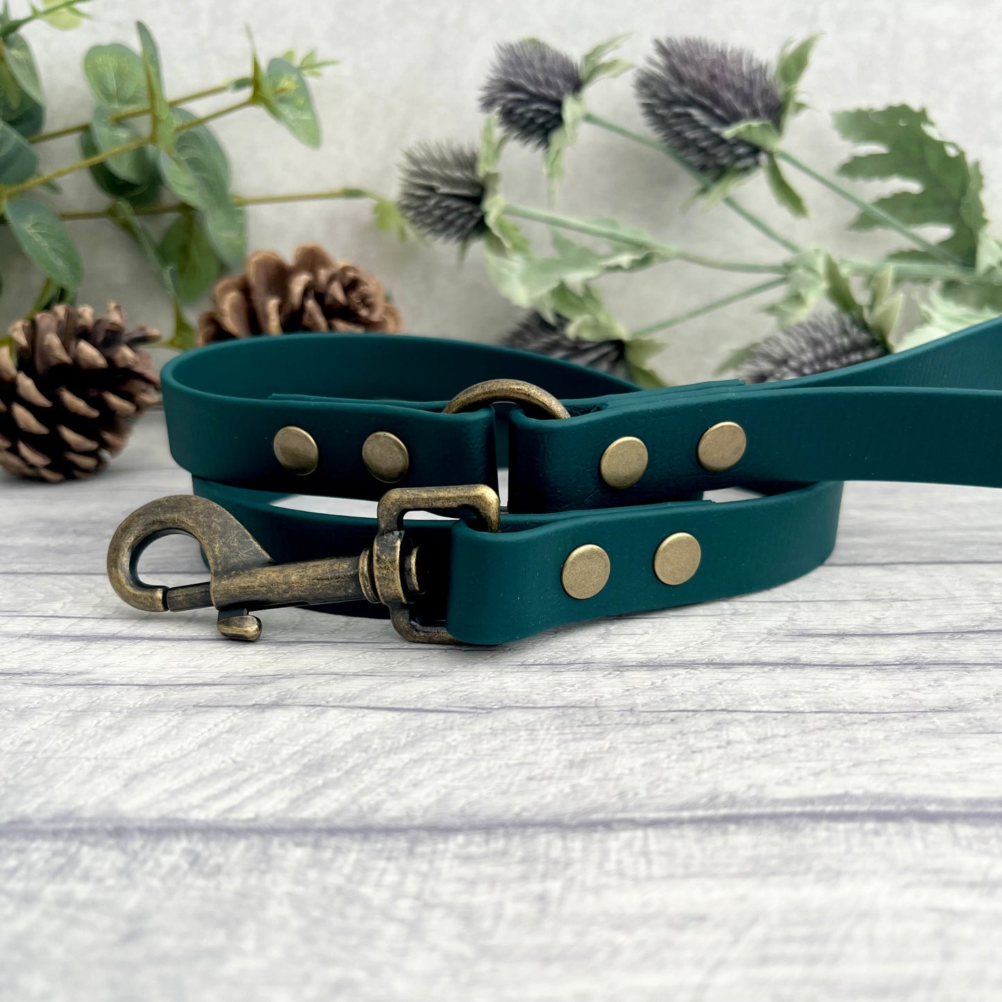 Dark Green Biothane lead with Antique Brass Hardware. An O-ring connects the handle to the lead with double ended rivets fixing it together. A Snap Clip is fixed with double ended rivets. The lead has a soft leather appearance.