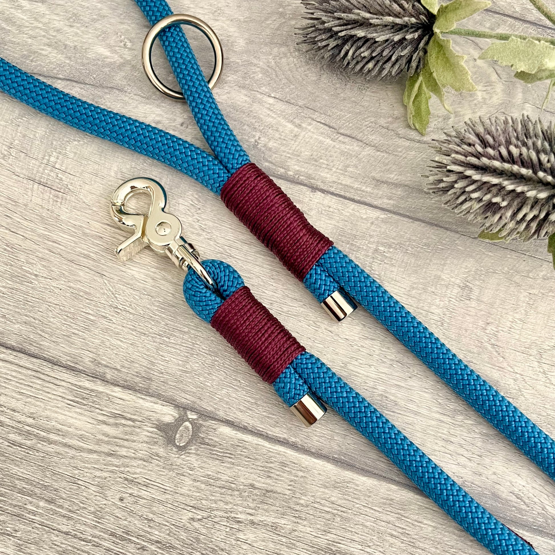 Lapis Blue rope lead with Aubergine whipping securing a swivel clip at one end with whipping securing a handle at the other. The ends of the rope ends are finished with metal end caps. All hardware is in Silver