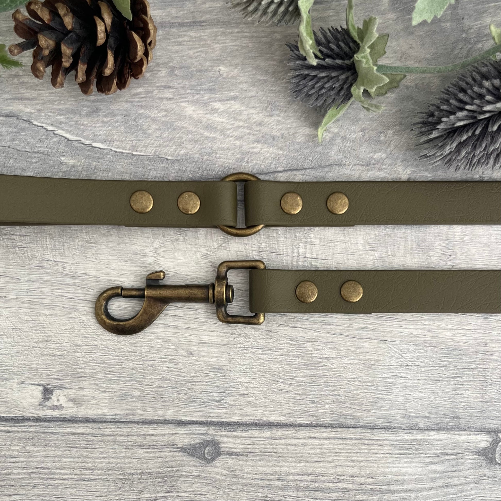 Military Olive Green Biothane lead with Antique Brass Hardware. An O-ring connects the handle to the lead with double ended rivets fixing it together. A Snap Clip is fixed with double ended rivets. The lead has a soft leather appearance.