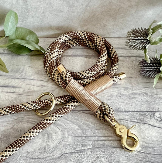 Tan & Brown rope dog lead with Light Gold whipping securing a swivel clip at one end with whipping securing a handle at the other. The ends of the rope ends are finished with metal end caps. All hardware is in Gold