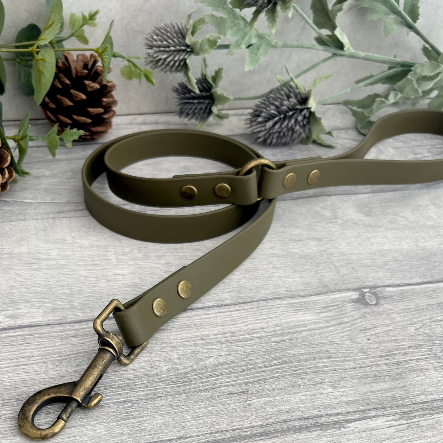 Military Olive Green Biothane lead with Antique Brass Hardware. An O-ring connects the handle to the lead with double ended rivets fixing it together. A Snap Clip is fixed with double ended rivets. The lead has a soft leather appearance.