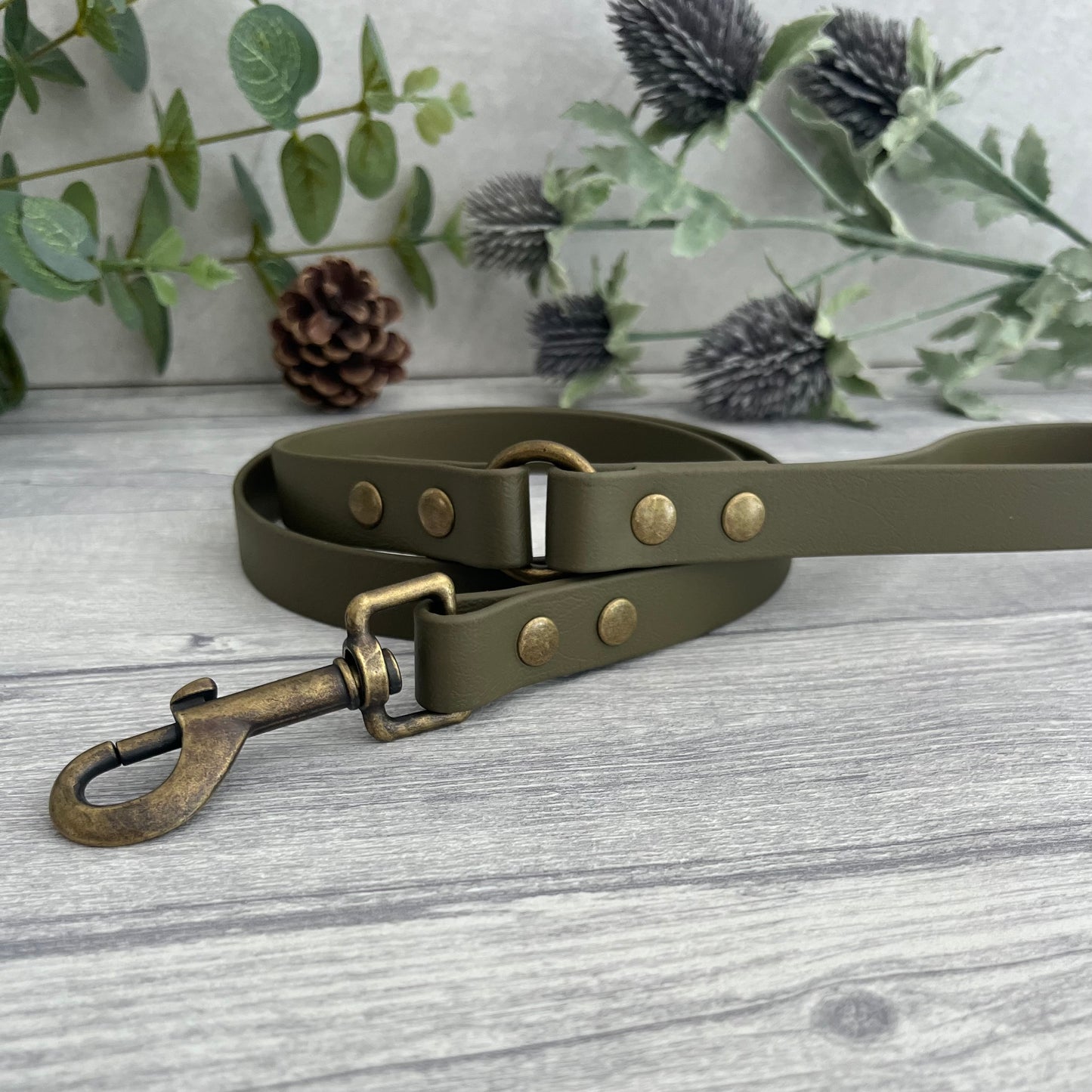 Military Olive Green Biothane lead with Antique Brass Hardware. An O-ring connects the handle to the lead with double ended rivets fixing it together. A Snap Clip is fixed with double ended rivets. The lead has a soft leather appearance.