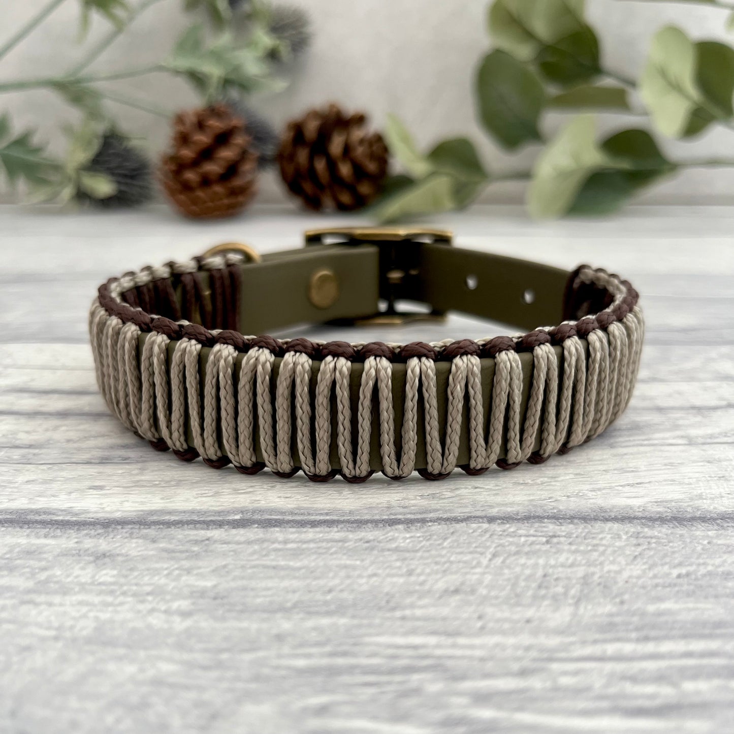 Military Olive Green Biothane collar wrapped in Tan & Brown PPM cord. The collar is fastened with a buckle and D-ring. The hardware is in Antique Brass