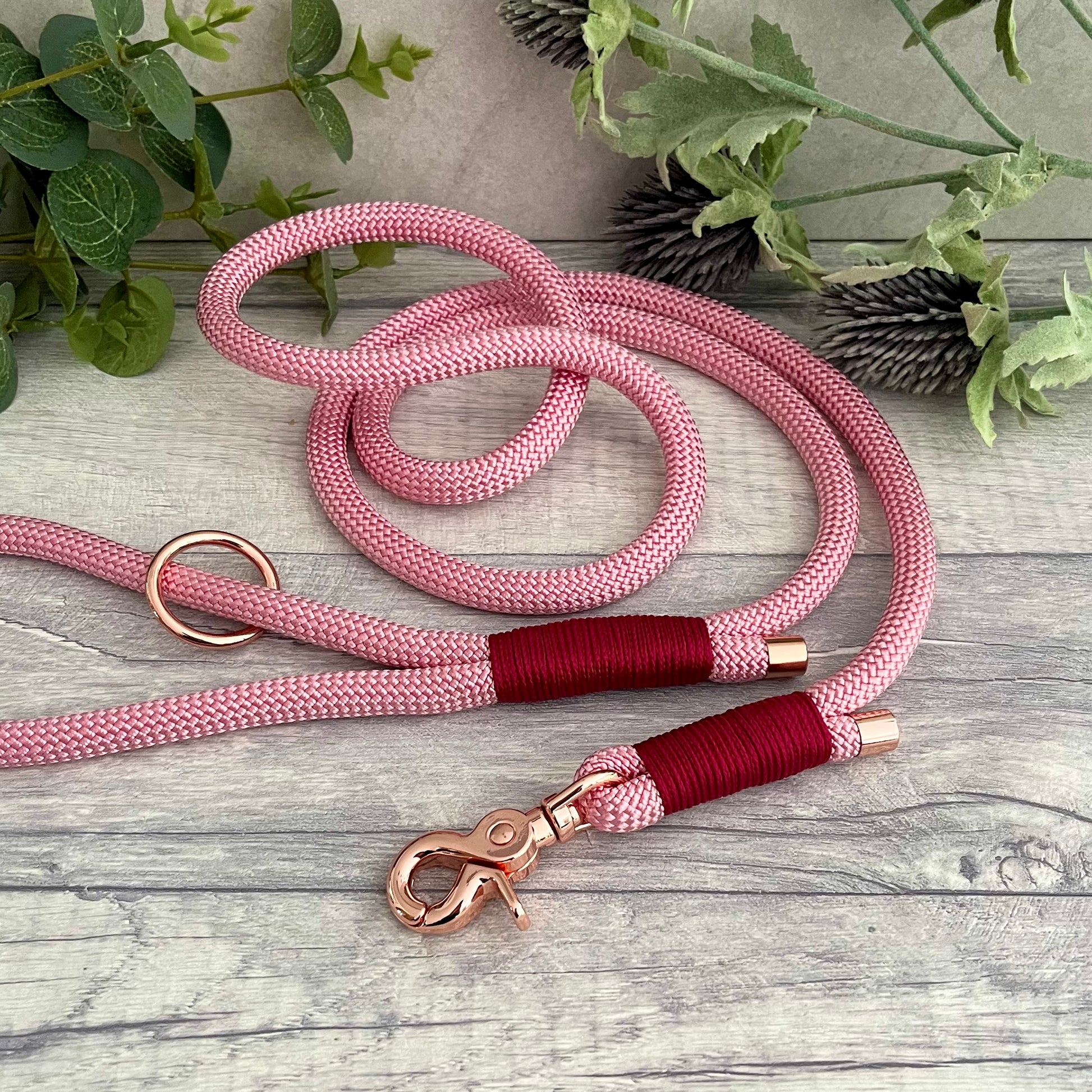 Pink rope lead with Raspberry whipping securing a swivel clip at one end and fastening a handle at the other. The handle has an O-ring attached. Each end of the rope is finished with a metal end cap. All hardware for this lead is in Rose Gold