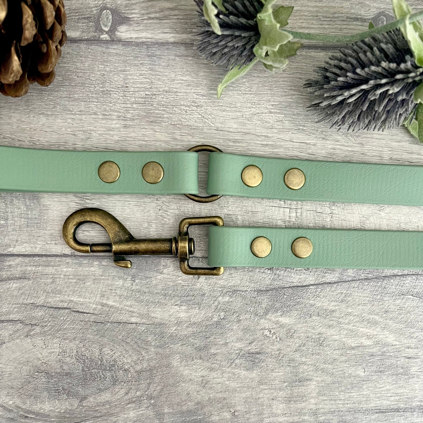 Sage Green Biothane lead with Antique Brass Hardware. An O-ring connects the handle to the lead with double ended rivets fixing it together. A Snap Clip is fixed with double ended rivets. The lead has a soft leather appearance.