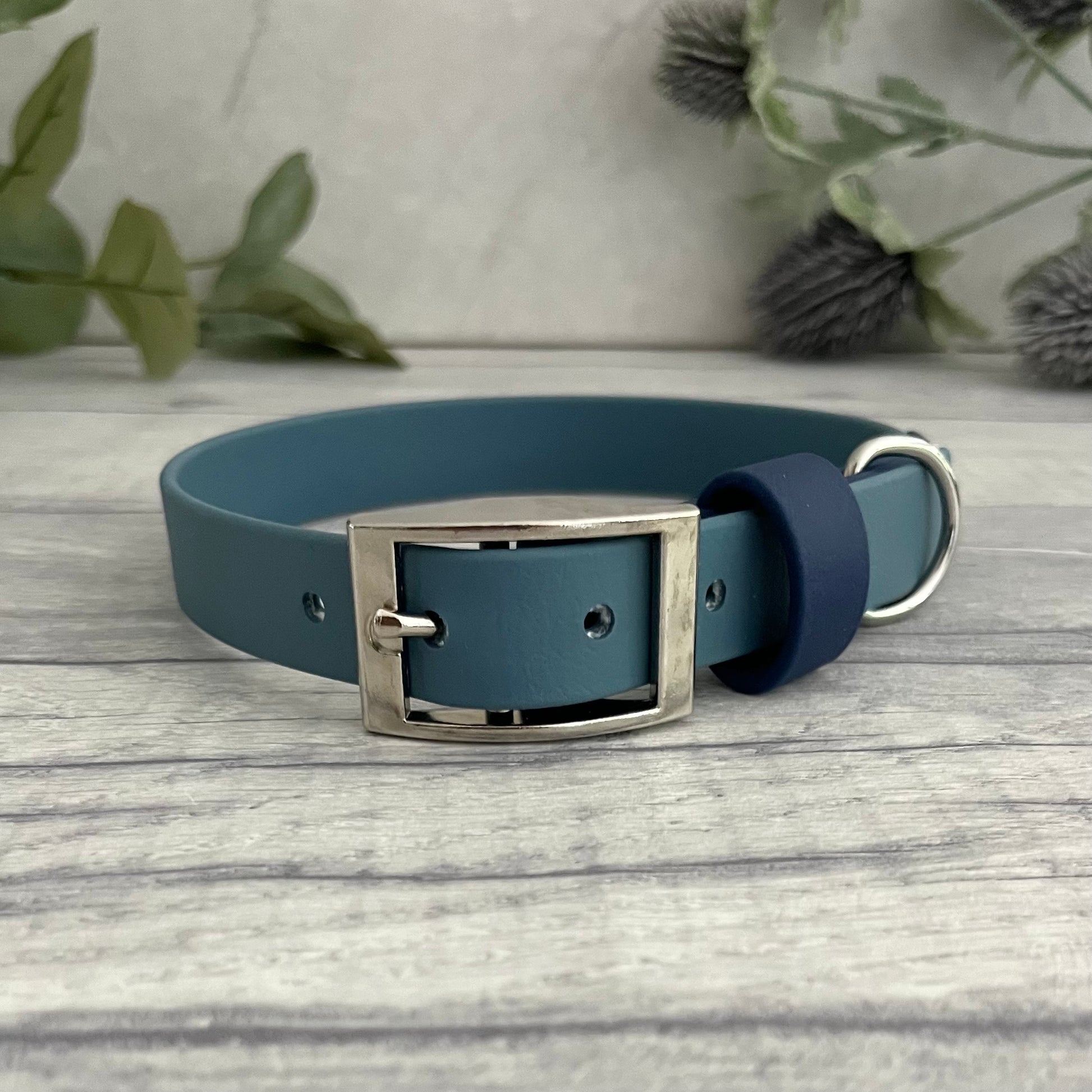 Two tone dog collar in Petrol Blue & Navy. The collar strap is two colours fixed together with a rivet. The collar has a Biothane strap keeper and a metal D-ring with 5 x punched holes. All hardware is Silver