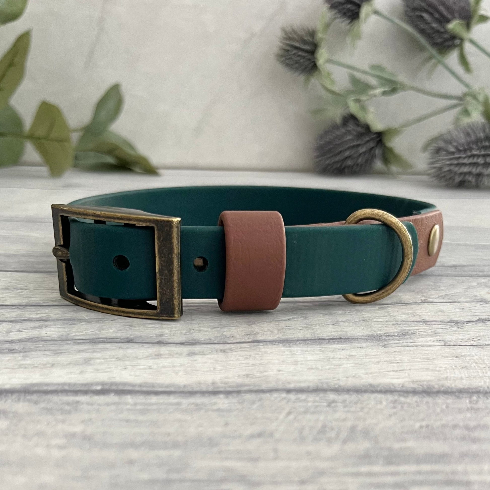 Two tone dog collar in Dark green & Brown. The collar strap is two colous fixed together with a rivet. The collar has a Biothane strap keeper and a metal D-ring with 5 x punched holes. All hardware is Antique Brass