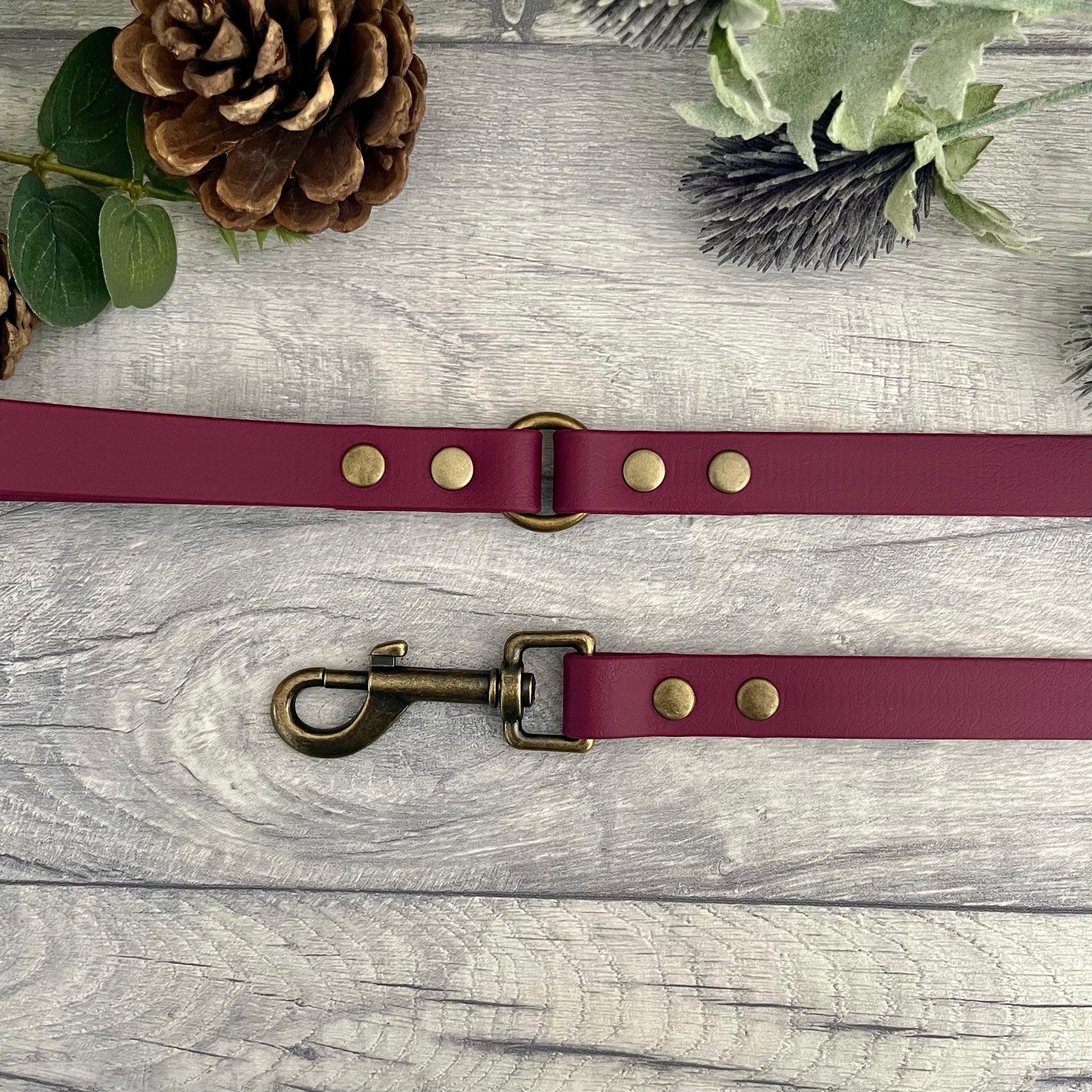 Wine Red Biothane lead with Antique Brass hardware. An O-ring connects the handle to the lead with double ended rivets fixing it together. A Snap Clip is fixed with double ended rivets. The lead has a soft leather appearance.