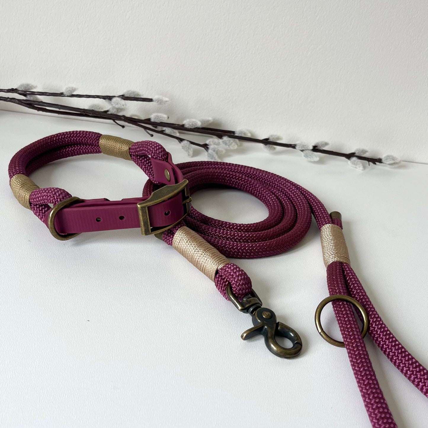 Purple dog rope collar and lead set on a white background with decorative branches.