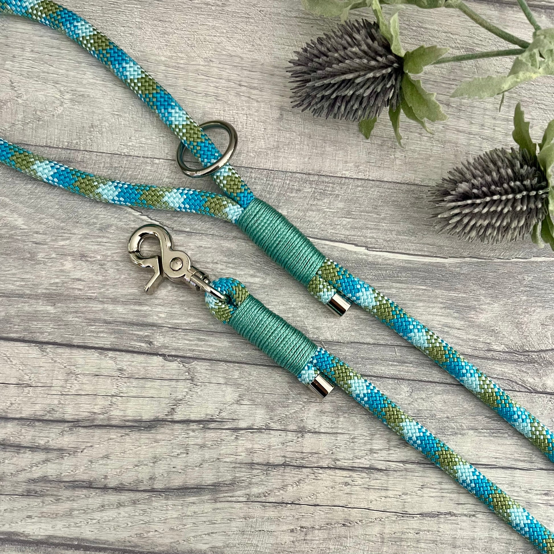 Bombay Blue rope lead with Sea Green whipping securing a swivel clip at one end and fastening a handle at the other. The handle has an O-ring attached. Each end of the rope is finished with a metal end cap. All hardware for this lead is in Silver