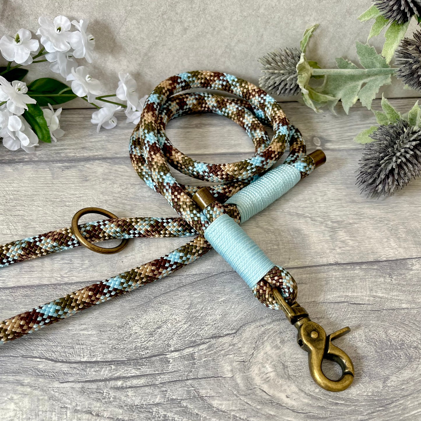 Tundra, Brown & Blue rope dog lead with Baby Blue whipping securing a swivel clip at one end and fastening a handle at the other. The handle has an O-ring attached. Each end of the rope is finished with a metal end cap. All hardware for this lead is in Antique Brass
