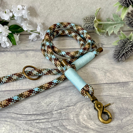 Tundra, Brown & Blue rope dog lead with Baby Blue whipping securing a swivel clip at one end and fastening a handle at the other. The handle has an O-ring attached. Each end of the rope is finished with a metal end cap. All hardware for this lead is in Antique Brass