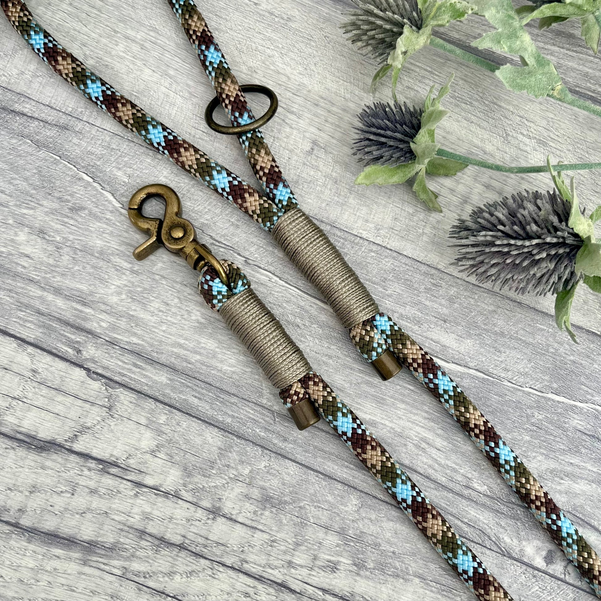 Tundra, Brown & Blue rope dog lead with Gold Brown whipping securing a swivel clip at one end and fastening a handle at the other. The handle has an O-ring attached. Each end of the rope is finished with a metal end cap. All hardware for this lead is in Antique Brass