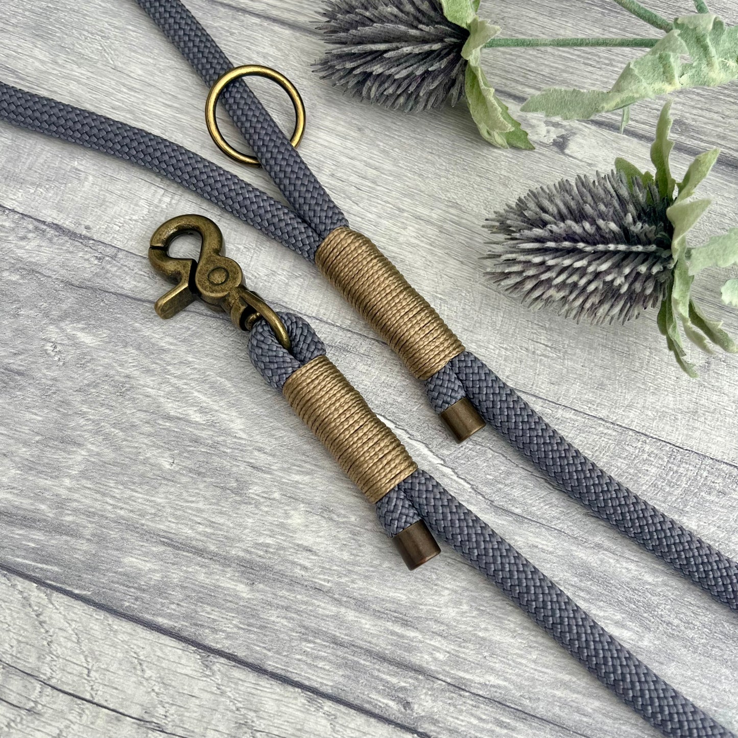 Charcoal Grey rope lead with Gold Brown whipping securing a swivel clip at one end and fastening a handle at the other. The handle has an O-ring attached. Each end of the rope is finished with a metal end cap. All hardware for this lead is in Antique Brass