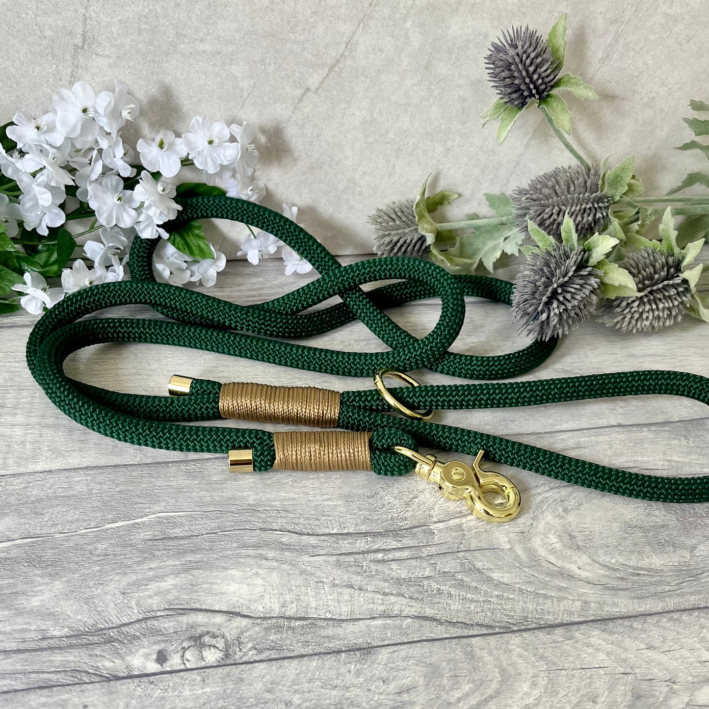 Dark Green rope dog lead with Gold Brown coloured whipping securing a swivel clip at one end and fastening a handle at the other. The handle has an O-ring attached. Each end of the rope is finished with a metal end cap. All hardware for this lead is in Gold