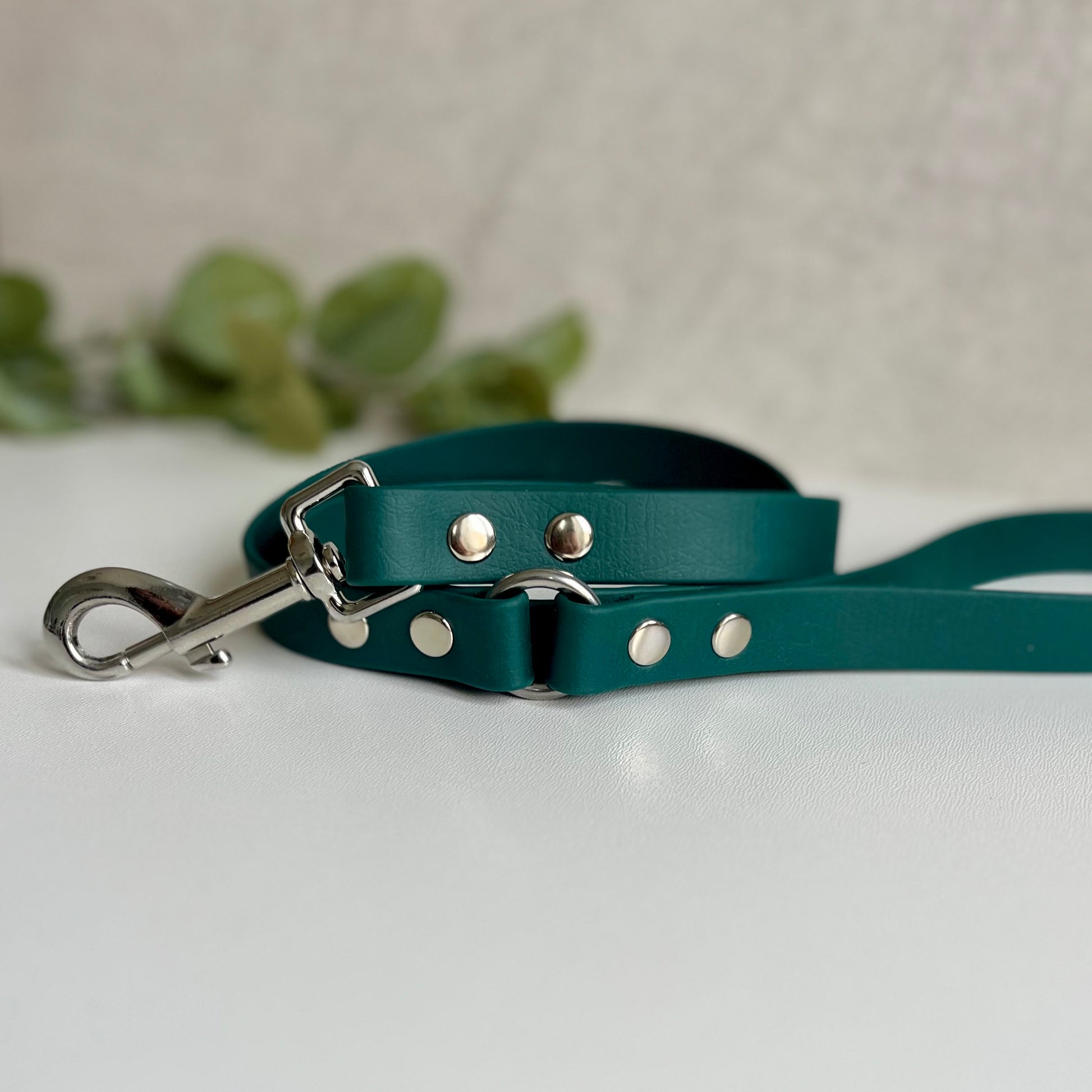 Dark Green Biothane lead with Silver Hardware. An O-ring connects the handle to the lead with double ended rivets fixing it together. A Snap Clip is fixed with double ended rivets. The lead has a soft leather appearance.