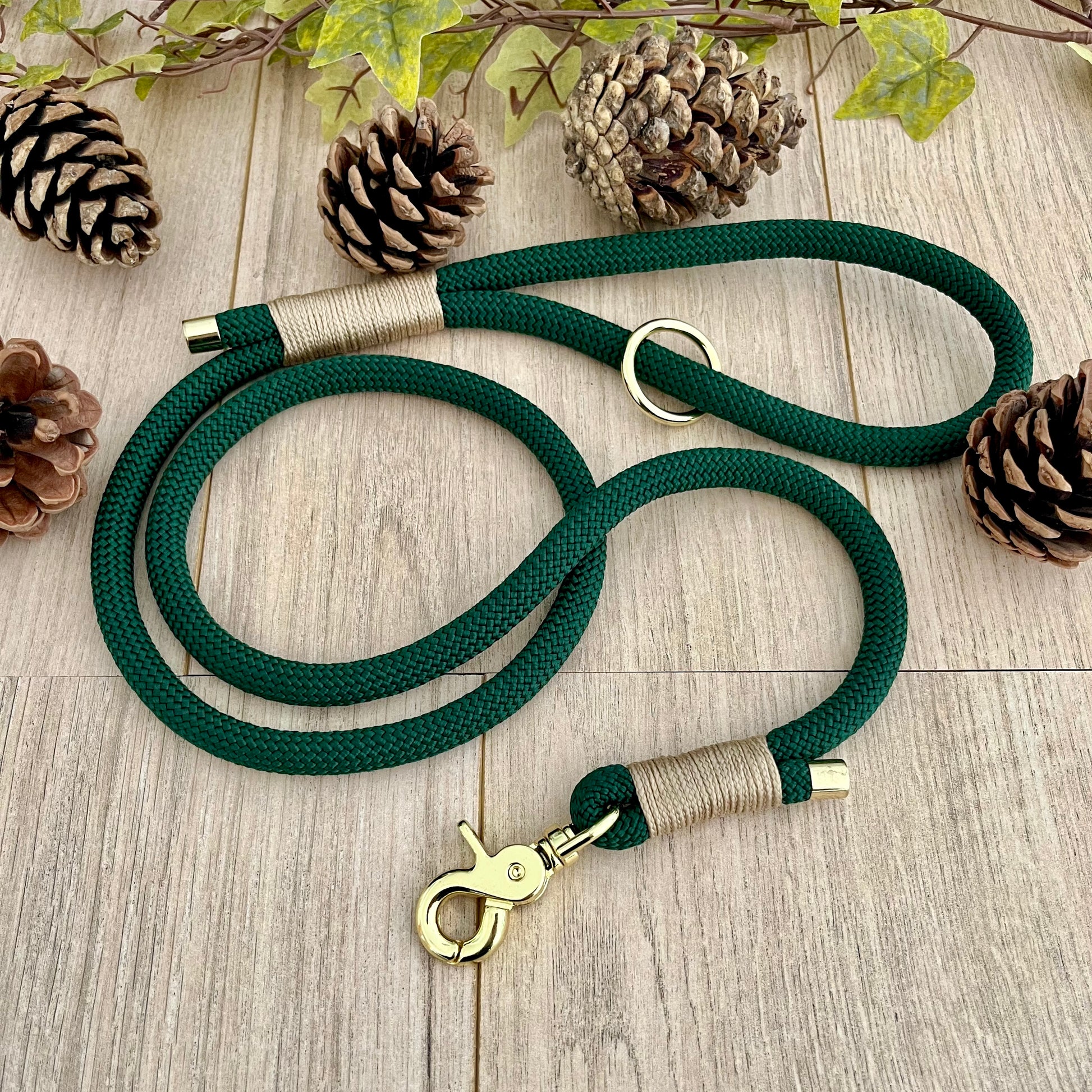Dark Green rope dog lead with Light Gold coloured whipping securing a swivel clip at one end and fastening a handle at the other. The handle has an O-ring attached. Each end of the rope is finished with a metal end cap. All hardware for this lead is in Gold