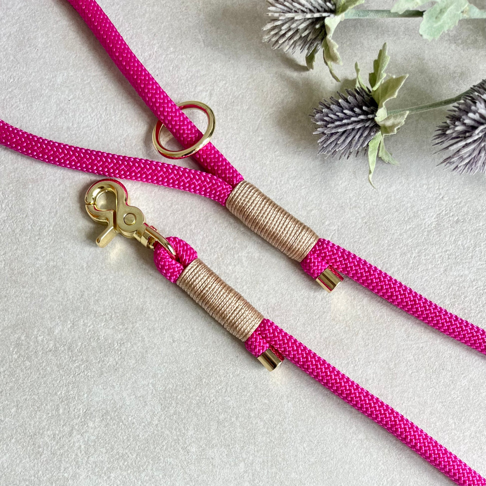 Fuchsia Pink rope lead with Light Gold whipping securing a swivel clip at one end and fastening a handle at the other. The handle has an O-ring attached. Each end of the rope is finished with a metal end cap. All hardware for this lead is in Gold