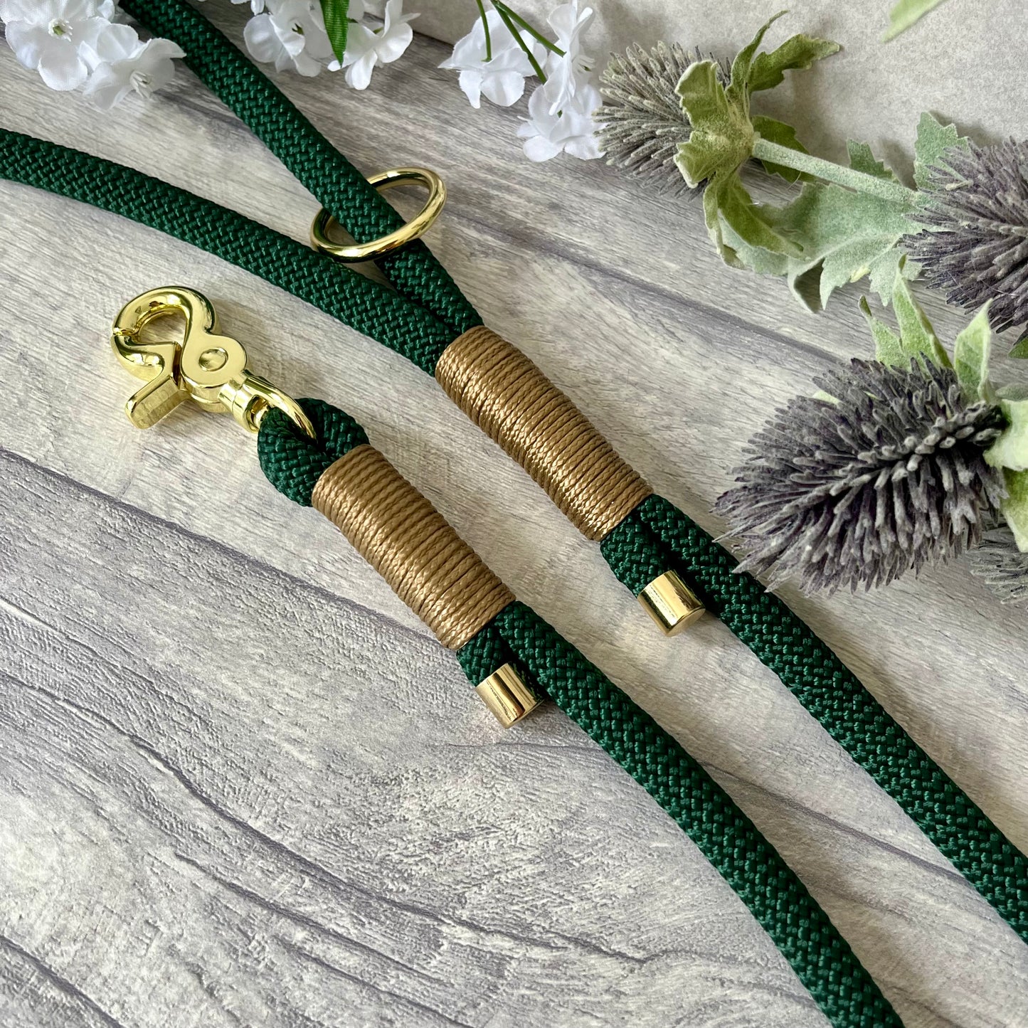 Dark Green rope dog lead with Gold Brown coloured whipping securing a swivel clip at one end and fastening a handle at the other. The handle has an O-ring attached. Each end of the rope is finished with a metal end cap. All hardware for this lead is in Gold