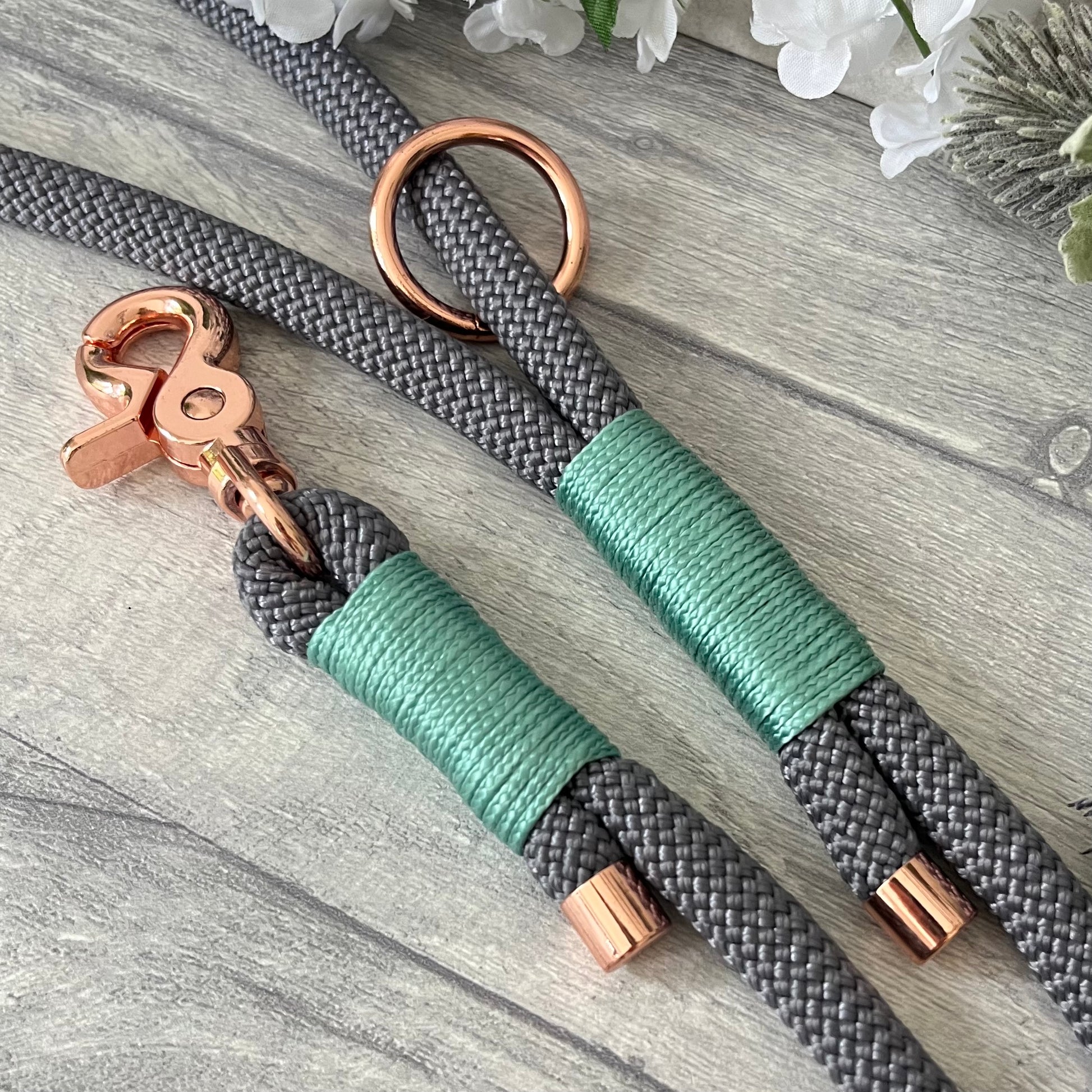 Charcoal Grey rope lead with Sea Green whipping securing a swivel clip at one end and fastening a handle at the other. The handle has an O-ring attached. Each end of the rope is finished with a metal end cap. All hardware for this lead is in Rose Gold