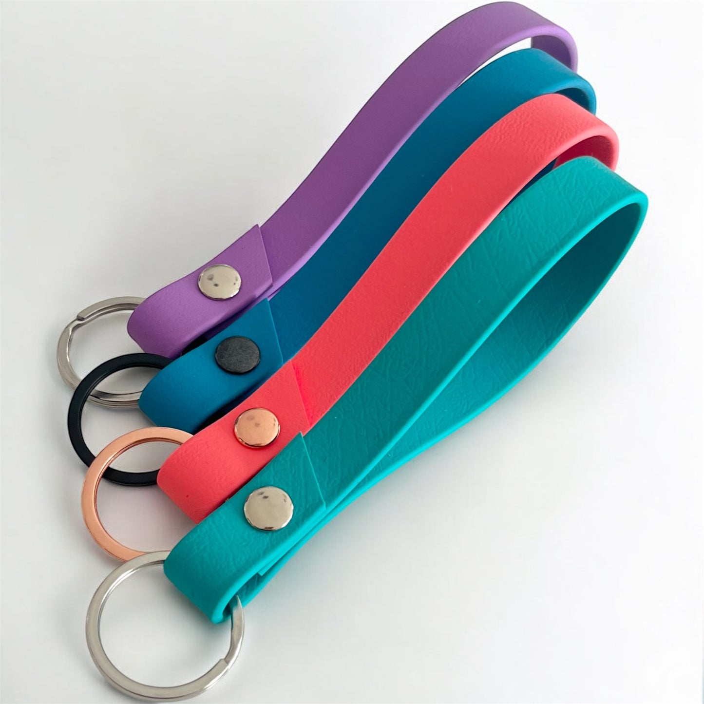 four colourful biothane key rings on a light surface