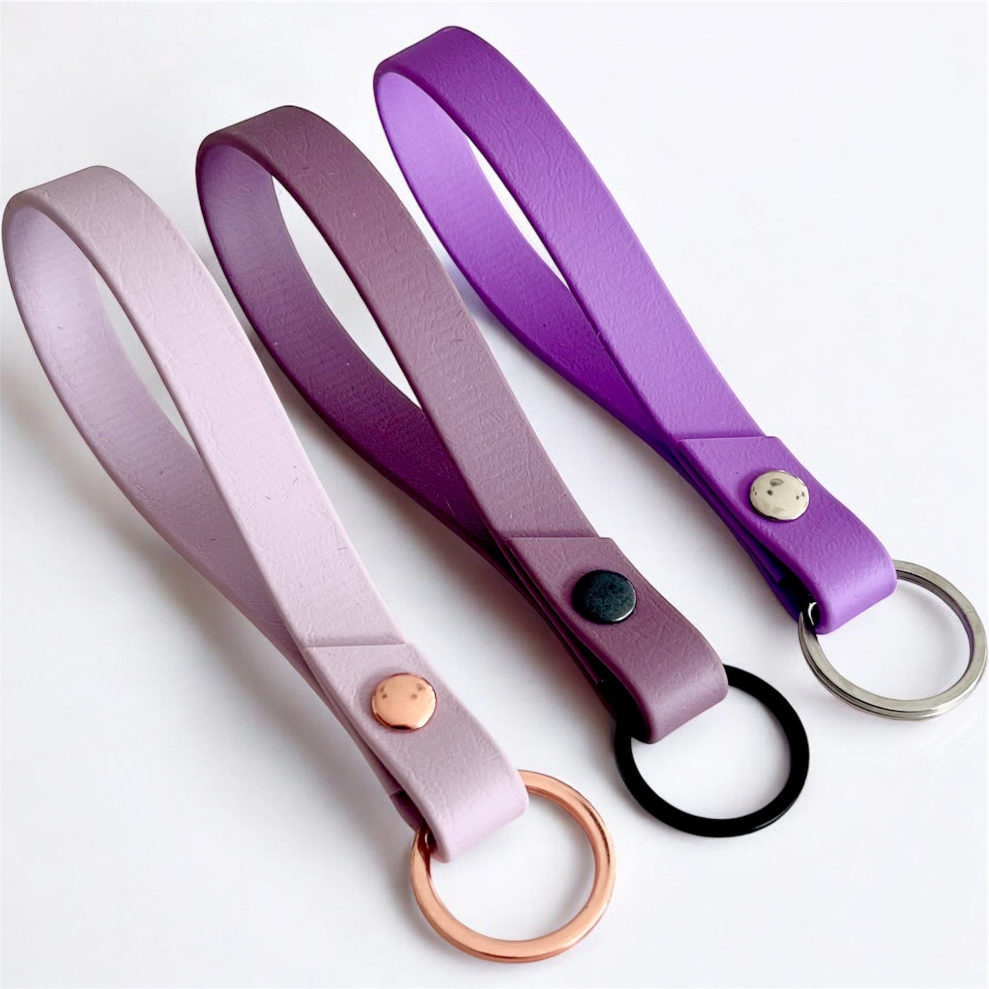three colourful biothane key rings on a light surface