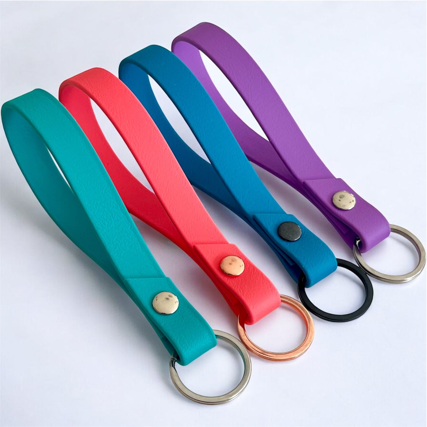 four colourful biothane key rings on a light surface