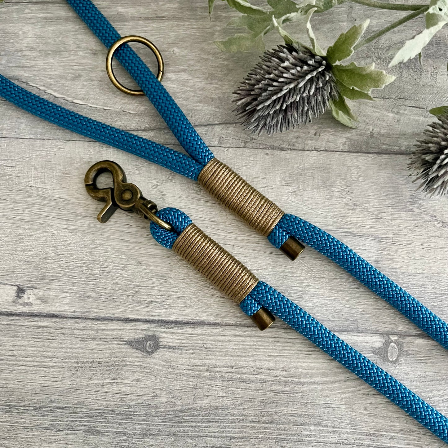 Lapis Blue rope lead with Gold Brown whipping securing a swivel clip at one end with whipping securing a handle at the other. The ends of the rope ends are finished with metal end caps. All hardware is in Antique Brass